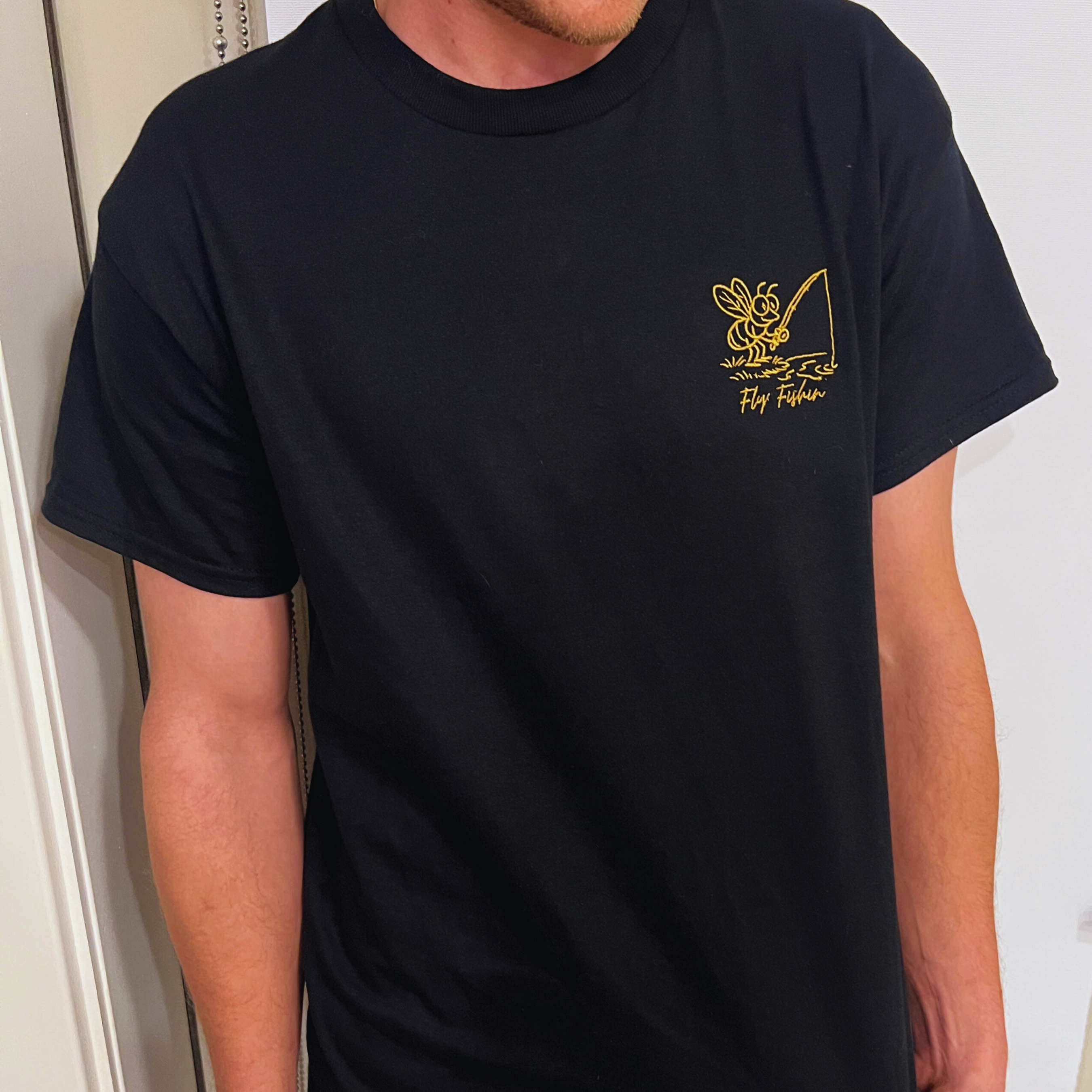 Person wearing a black t-shirt with a yellow logo on a white background